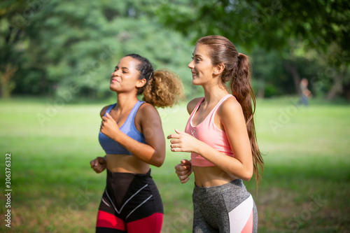 Healthy beautiful sportswoman wearing tracksuit jogging in the park, African american women and Caucasian women