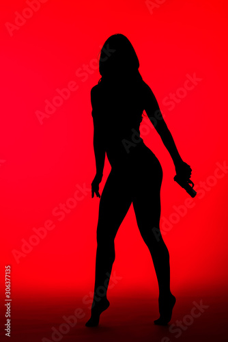 silhouette of criminal woman in bodysuit holding gun isolated on red