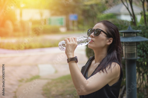 A relax woman drinking water in the park outdoor, finished her job.