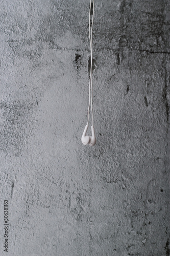 White earphone hanging on grey background © elenaara