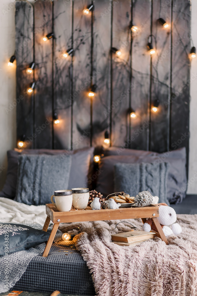 Cozy room with table, a cup on the bed, marshmallow and cookies, cozy knitted blanket. New Year 2020, flat lay. Christmas composition with a mug, tray, a deer and a Christmas tree. Cozy room with table, a cup on the bed, marshmallow and cookies, cozy knitted blanket. New Year 2020, flat lay. Christmas composition with a mug, tray, a deer and a Christmas tree.