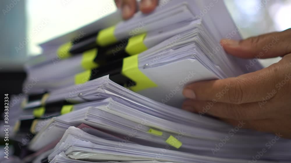 Stacks documents of paper files, Businessman hands working in messy bureaucracy and searching information on office, Accounting budget report file, arranging unfinished of paperwork on busy overwork