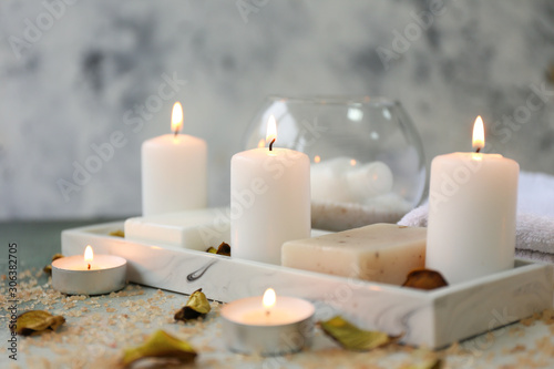Glowing candles with soap on table