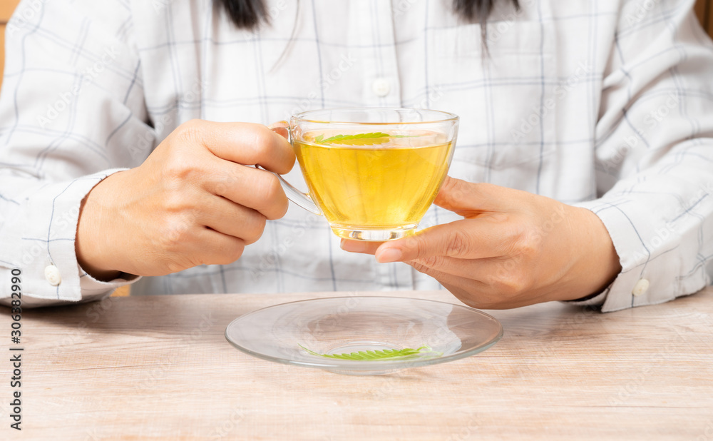 Woman drinking tea made from cannabis leaves ,A cup of hot marijuana tea with buds and leaves. Woman drinking tea made from cannabis leaves ,A cup of hot marijuana tea with buds and leaves.