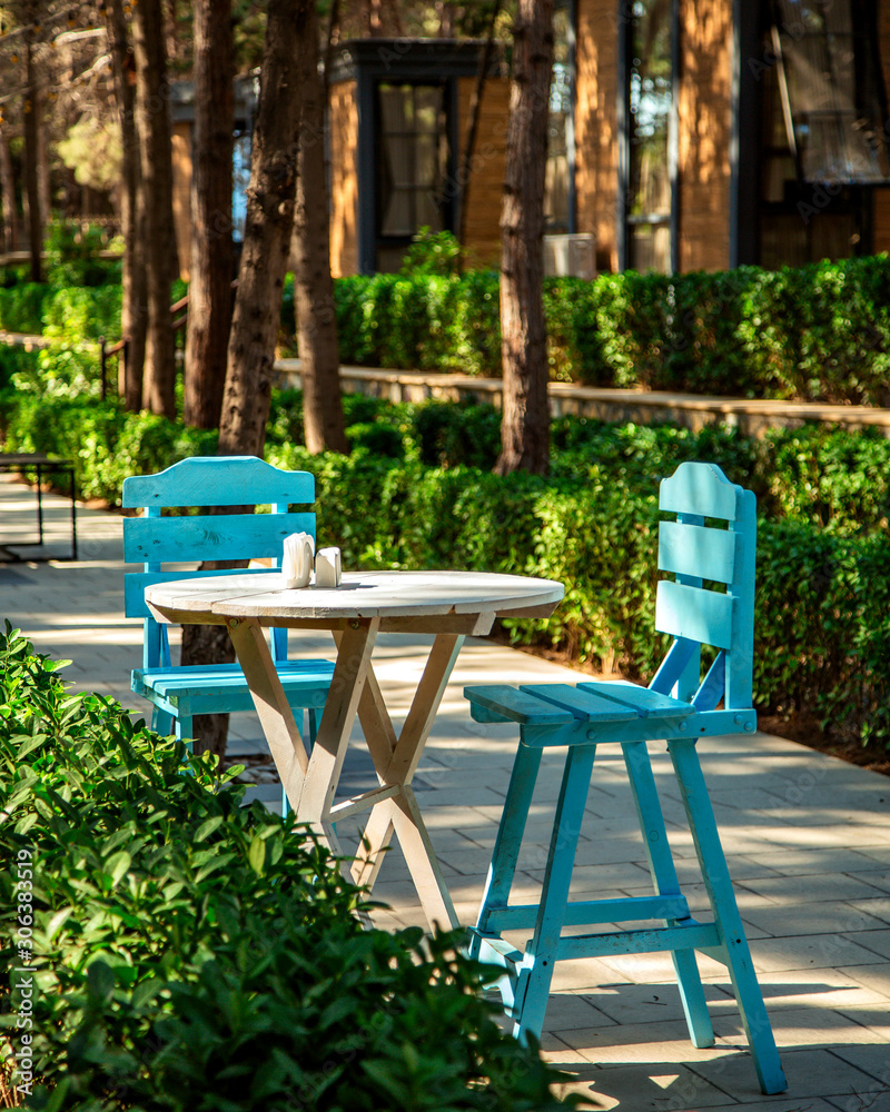 two turquoise chairs and wood round table in the restaurant garden