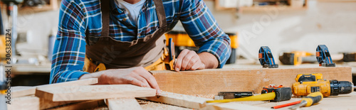 panoramic shot of carpenter touching wooden dowel