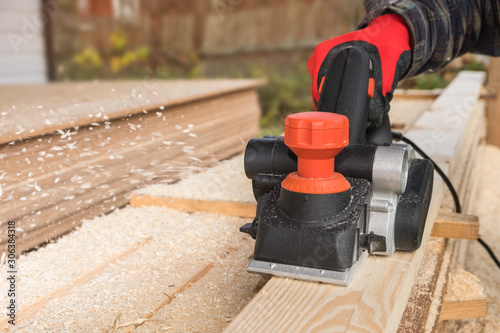 carpenter polishes boards with an electric jack planer at a private house construction site photo