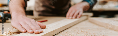 Fényképezés Panoramic shot of carpenter touching wooden plank