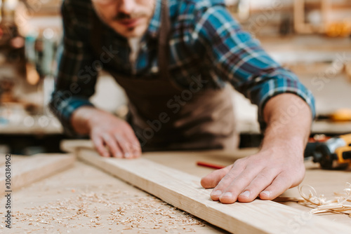 Obraz na płótnie Cropped view of carpenter touching wooden plank