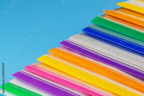 A row of multi-colored plastic folders for paper on a blue background.