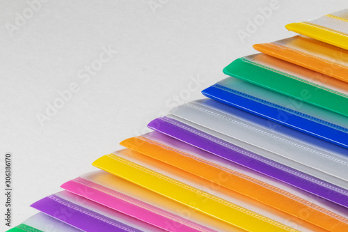 A row of multi-colored plastic folders for paper on a white background.