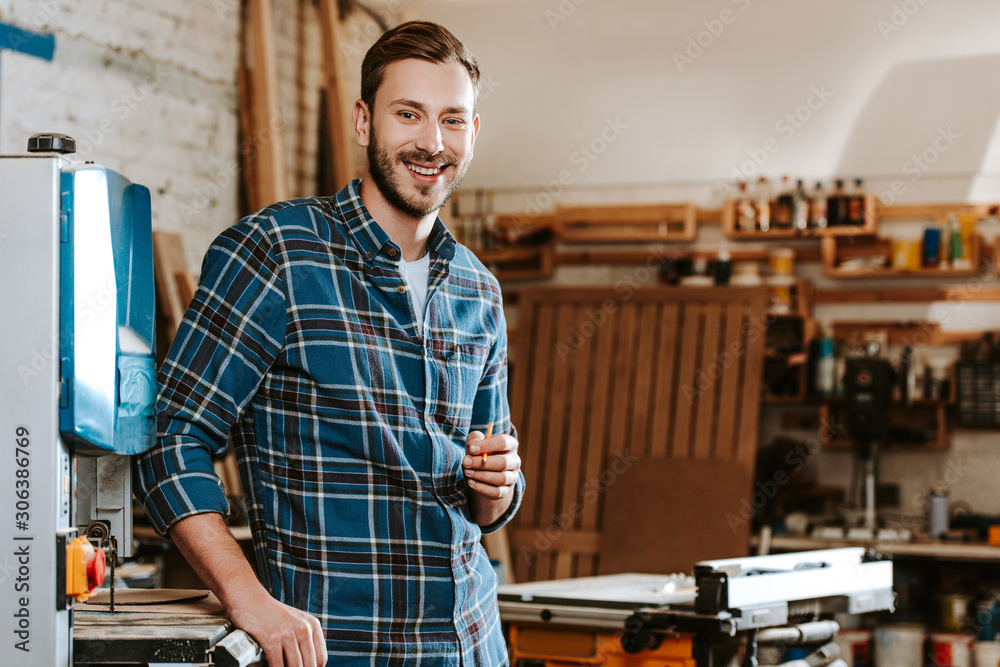 cheerful carpenter holding pencil in workshop cheerful carpenter holding pencil in workshop