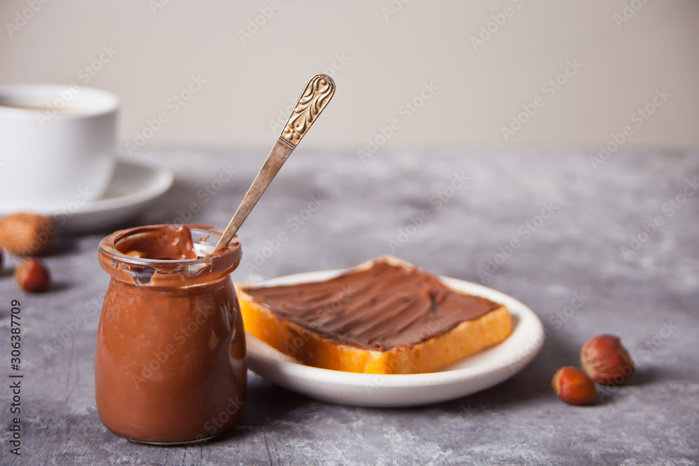 Bread toast with chocolate cream butter, jar of chocolate cream on the concrete background Bread toast with chocolate cream butter, jar of chocolate cream on the concrete background