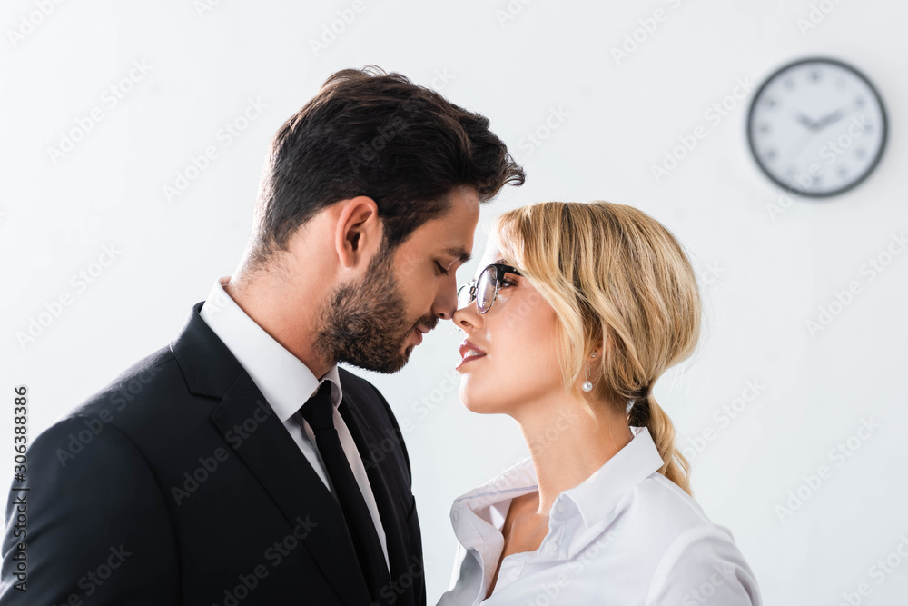Side view of business couple looking at each other while flirting in office Side view of business couple looking at each other while flirting in office