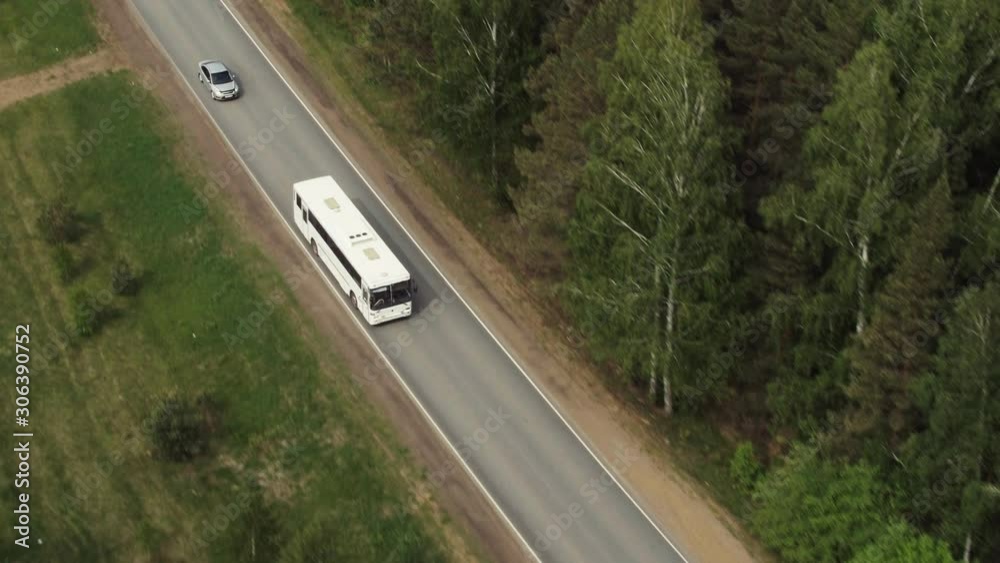 White alone bus driving on freeway through dense forest at summer day - Aerial drone view White alone bus driving on freeway through dense forest at summer day - Aerial drone view