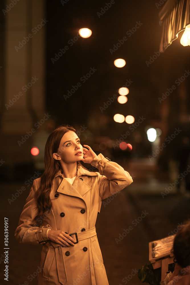 pensive young woman in trench coat 