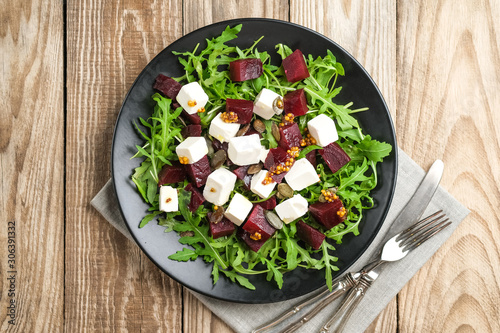 Salad with beetroot, feta cheese, arugula and spicy dressing on a rustic background top view. Healthy food. Top view. Copy space.