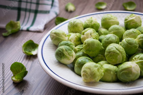 organic raw and fresh brussel sprouts on a plate with a wooden background