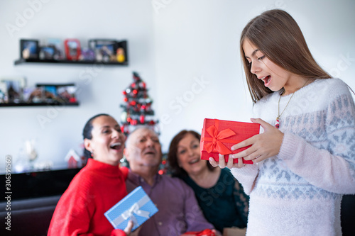 Multi generation family giving Christmas gifts on the sofa at home