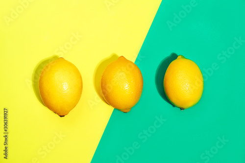 Creative pattern made of lemons on bright yellow and trendy green blue background.