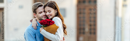 panoramic shot of happy girl embracing boyfriend while holding bouquet of roses photo
