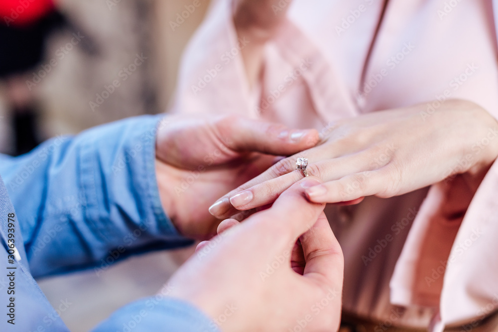 cropped view of man putting wedding ring on finger of girlfriend cropped view of man putting wedding ring on finger of girlfriend