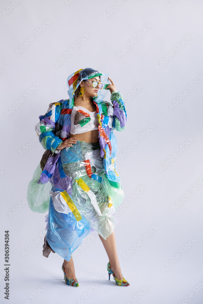 Woman wearing plastic on white background. Female model in clothes and shoes made of garbage. Fashion, style, recycling, eco and environmental concept. Too much pollution, we're eating and taking it. Woman wearing plastic on white background. Female model in clothes and shoes made of garbage. Fashion, style, recycling, eco and environmental concept. Too much pollution, we're eating and taking it.