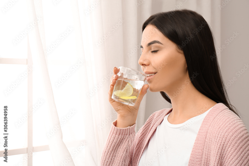 Beautiful young woman drinking fresh lemon water indoors Beautiful young woman drinking fresh lemon water indoors