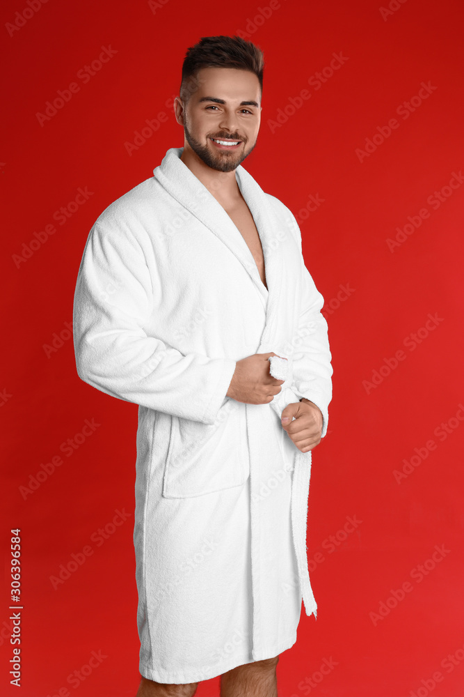 Happy young man in bathrobe on red background