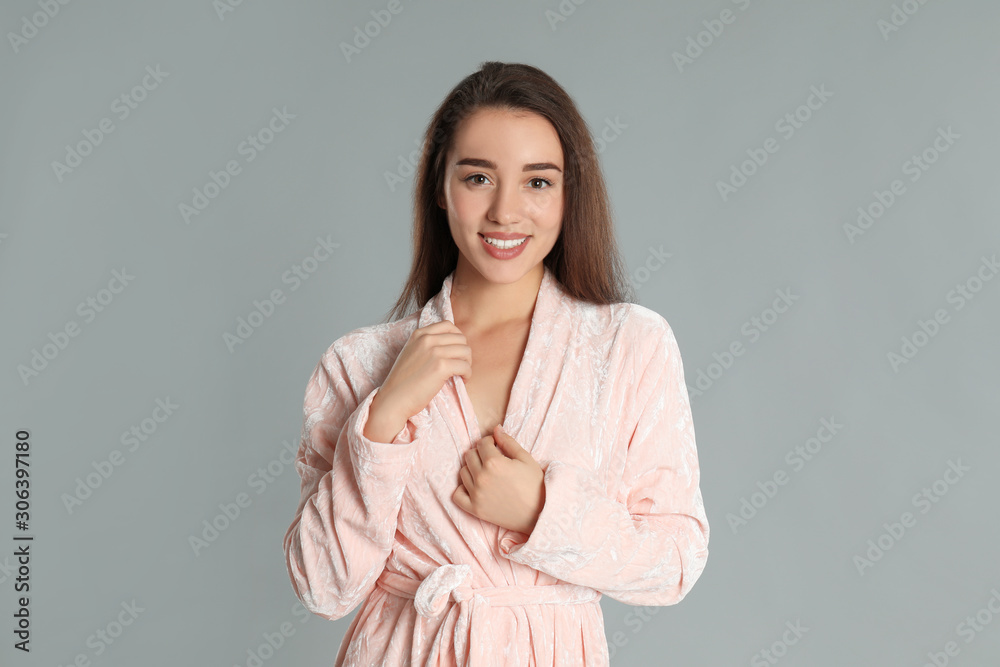 Obraz premium Beautiful young woman in bathrobe on grey background