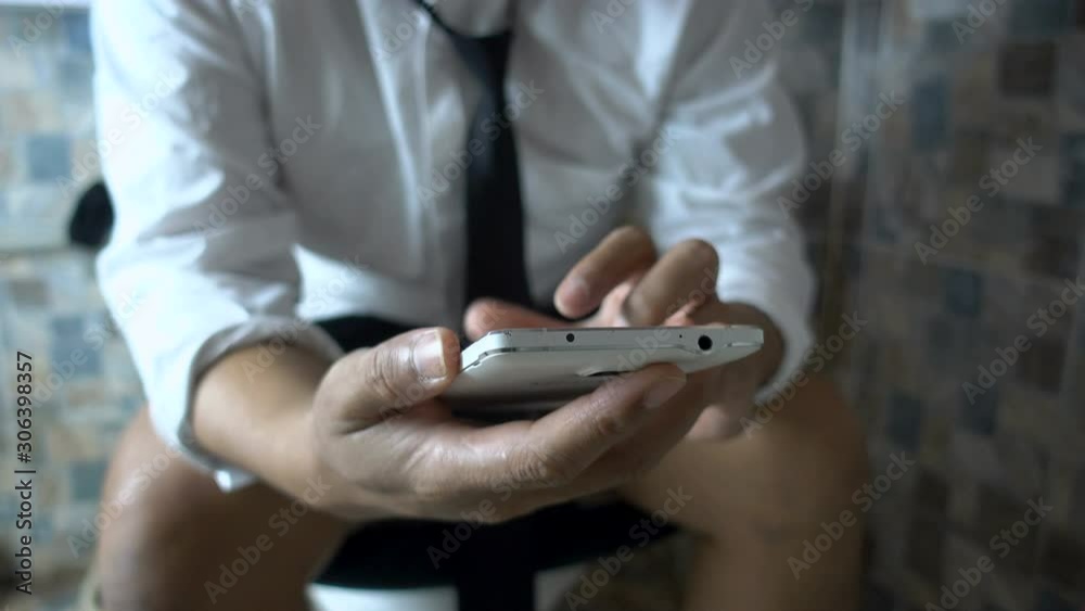 Businessman using smart phone in toilet Businessman using smart phone in toilet