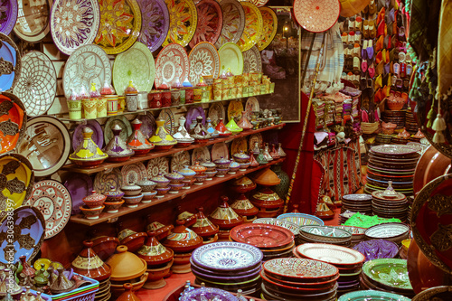 Colorful Moroccan ceramics and pottery displayed with typical slippers in the background in a shop in the Souks in the Medina of Marrakech, Morocco