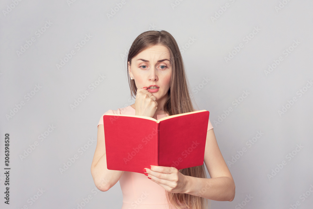 Amazed girl reads red book, portrait, copy space, toned Amazed girl reads red book, portrait, copy space, toned