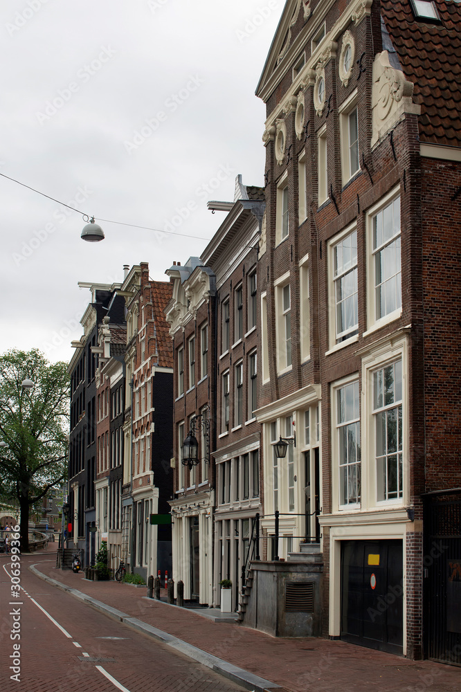 View of historical, traditional and typical buildings showing Dutch's architectural style in Amsterdam. It is a summer day with cloudy sky.