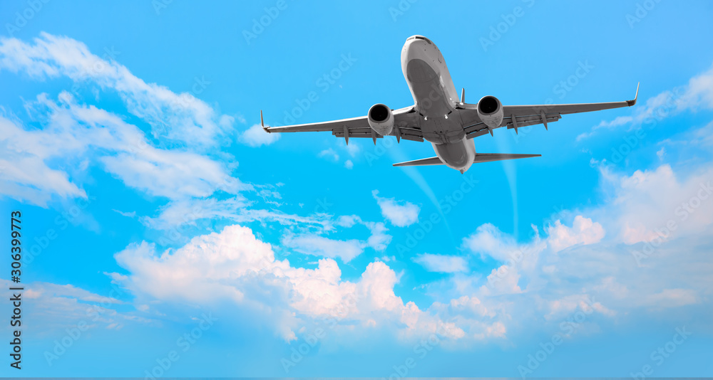 Naklejka premium White passenger airplane in the clouds - Travel by air transport