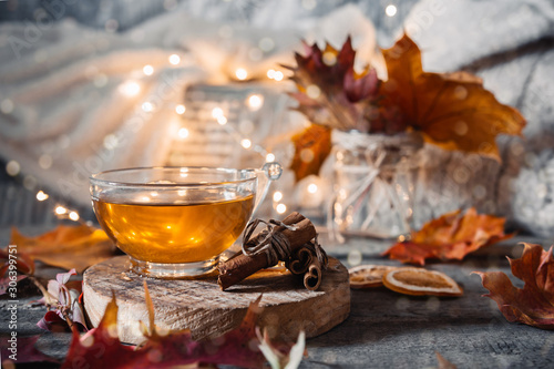 Cozy autumn or winter at home. A cup of tea, autumn casts a book a garland on a wooden table near a bed with warm plaids. Lifestyle autumn hygge lagom?concept of a holiday and autumn weekend. photo