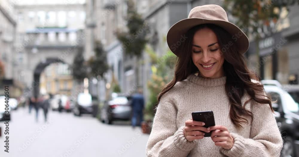 Beautiful young woman using phone on city street