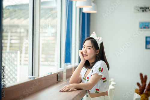 Free Download An Asian woman smiled in a coffee shop. She is bright and cute - GFXLoad