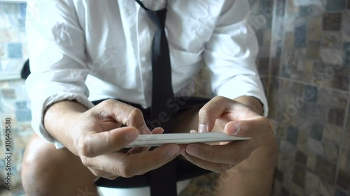 Businessman using smart phone in toilet
