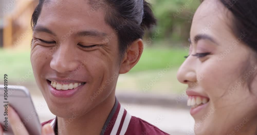Young attractive woman shows a funny picture to a young attractive man with braces. - Slow Motion - shot on RED Young attractive woman shows a funny picture to a young attractive man with braces. - Slow Motion - shot on RED