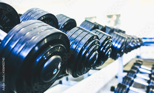 Fototapeta Naklejka Na Ścianę i Meble -  Heavy dumbbells lying in the raw in the gym. Fitness sport motivation. Happy healthy lifestyle living. Exercises with bars weights.