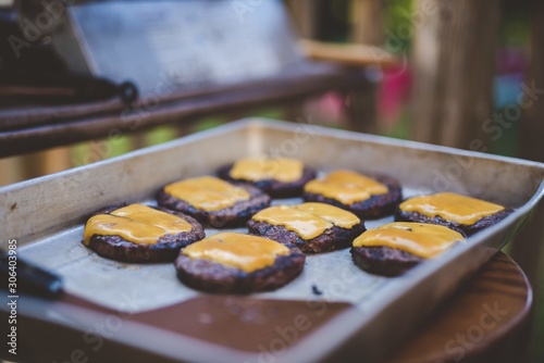 Selective focus shot of hamburger meats with cheese on a tray photo
