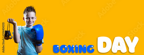 Severe boy in blue Boxing gloves on bright yellow background photo
