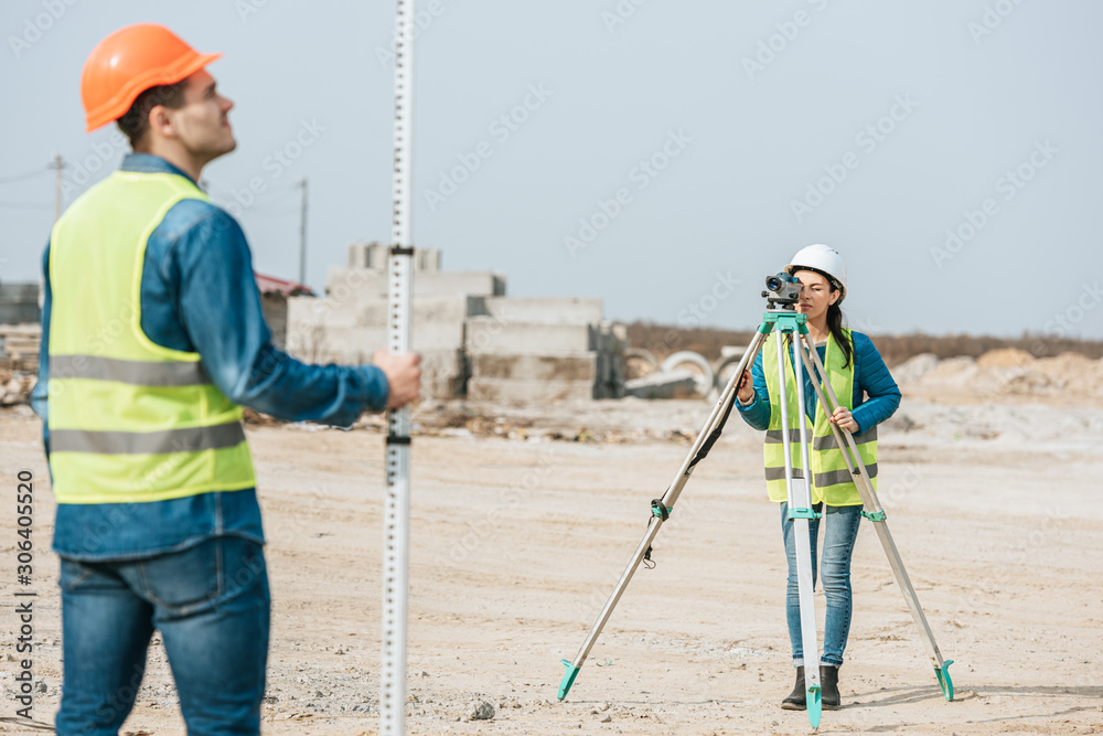 Selective focus of surveyors using digital level and ruler on construction site Selective focus of surveyors using digital level and ruler on construction site