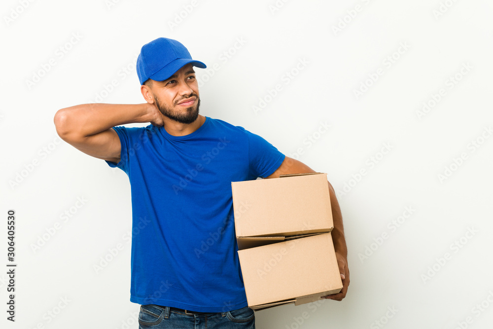 Young south-asian delivery man touching back of head, thinking and making a choice. Young south-asian delivery man touching back of head, thinking and making a choice.