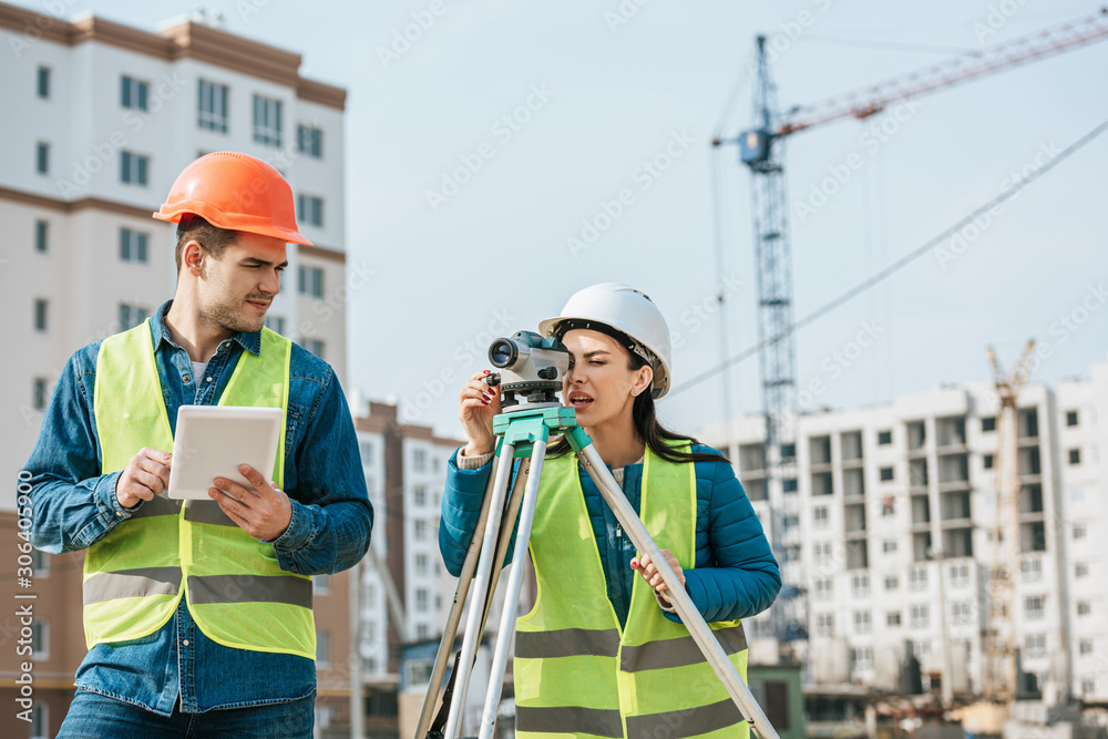 Surveyors working with digital tablet and measuring level on construction site Surveyors working with digital tablet and measuring level on construction site