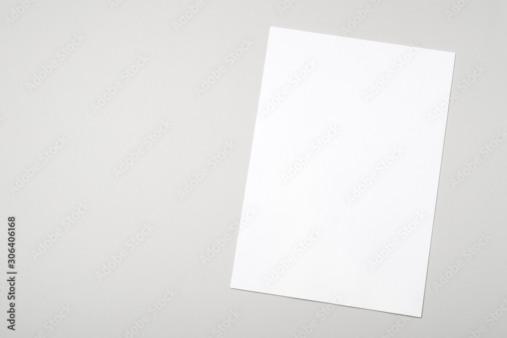 Fototapeta premium Blank white paper sheet for mock up on a gray background