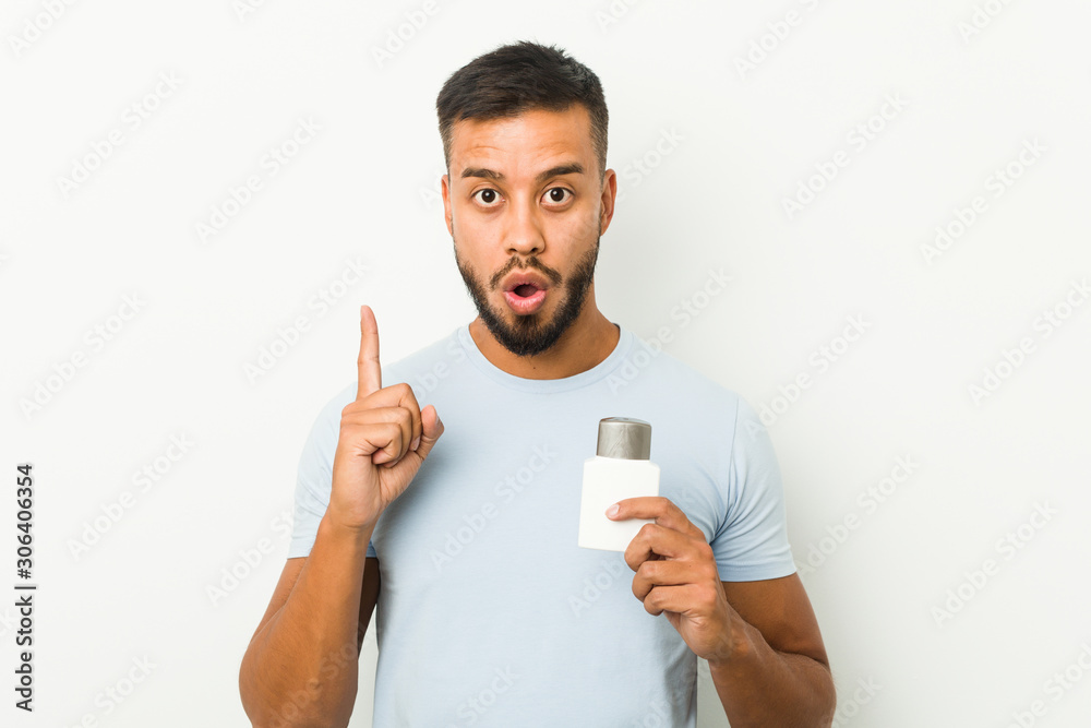 Young south-asian man holding an after shave cream having some great idea, concept of creativity. Young south-asian man holding an after shave cream having some great idea, concept of creativity.