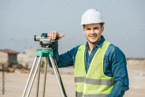 Smiling surveyor with digital level looking at camera