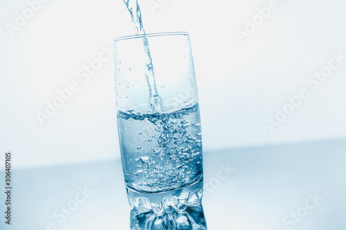 Drinking water poured into a glass isolated over blue abstract background